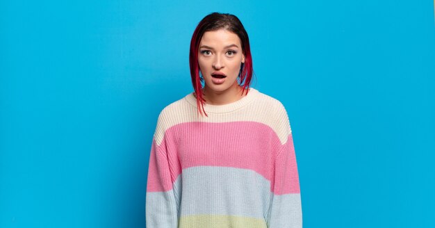 Young pretty woman gesturing on colored wall