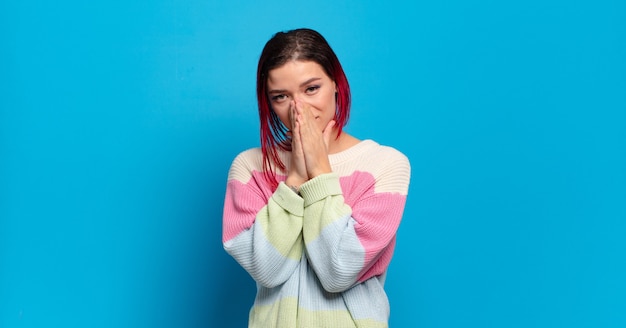 Young pretty woman gesturing on colored wall