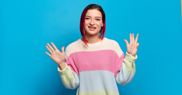 Young pretty woman gesturing on colored wall