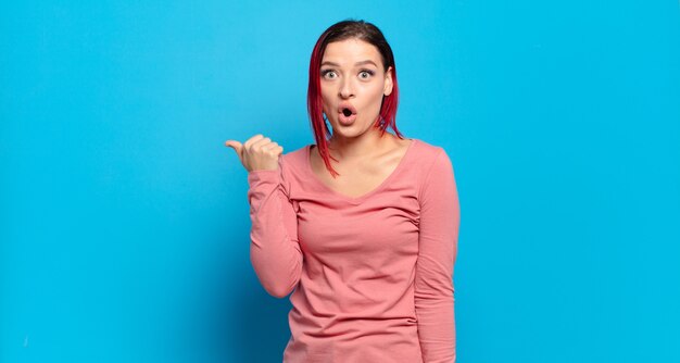 Young pretty woman gesturing on colored wall