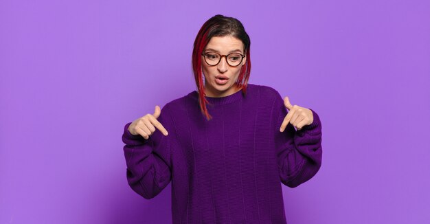 Young pretty woman gesturing on colored wall