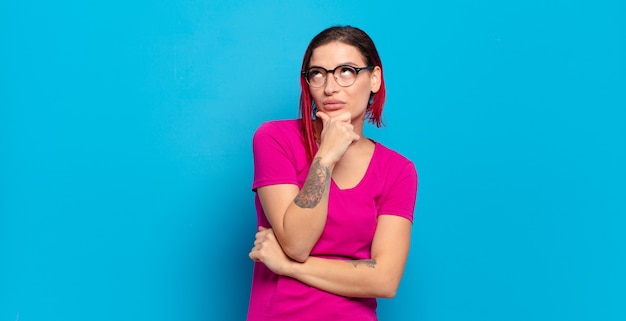 Young pretty woman gesturing on colored wall