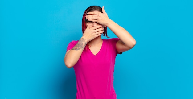 Young pretty woman gesturing on colored wall