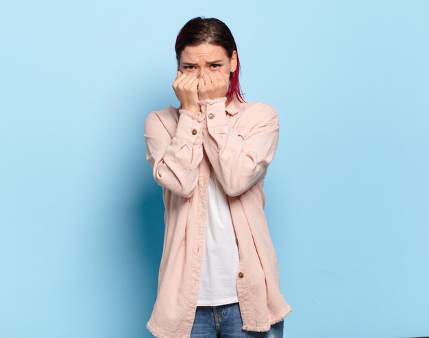 Young pretty woman gesturing on colored wall