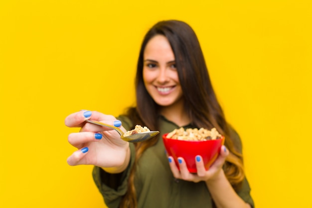 Young pretty woman having breakfast against orange wall