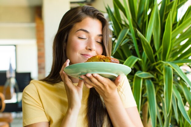 Foto giovane donna graziosa che mangia colazione a casa