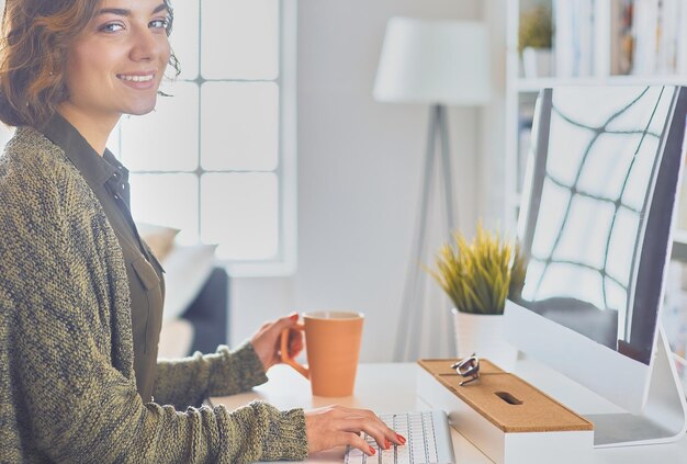 Young pretty woman having coffee and using laptop computer on sofa at home