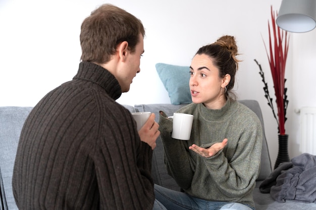 Young pretty woman having conversation with boyfriend and sharing a cup of coffee