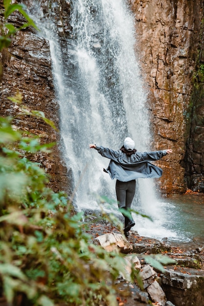 Young pretty woman hiking enjoying view of waterfall copy space