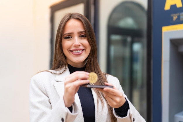 Young pretty woman holding a Bitcoin at outdoors