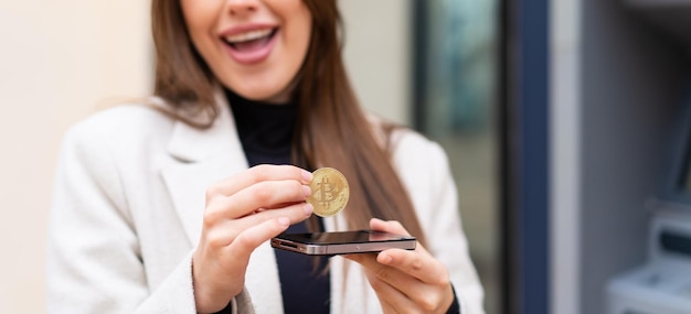 Young pretty woman holding a Bitcoin at outdoors