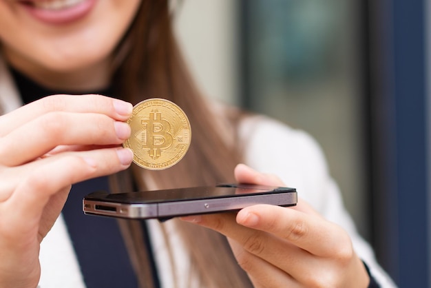 Giovane donna graziosa che tiene un bitcoin all'aperto