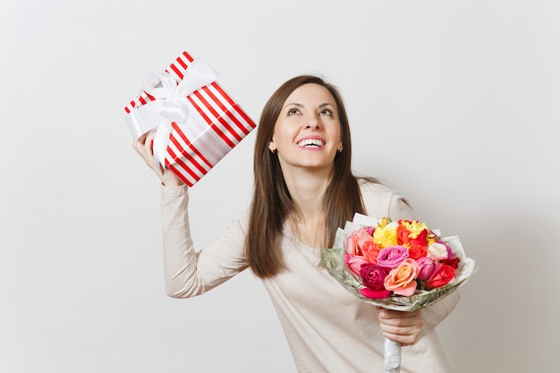 Young pretty woman holding bouquet of beautiful roses flowers, present box with gift isolated on white background. Copy space for advertisement. St. Valentines Day or International Women's Day concept