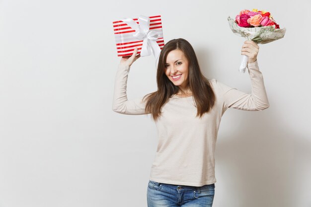 Young pretty woman holding bouquet of beautiful roses flowers, present box with gift isolated on white background. Copy space for advertisement. St. Valentines Day or International Women's Day concept