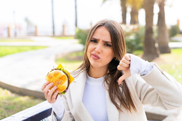 Young pretty woman holding a burger at outdoors