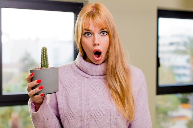 Young pretty woman holding a cactus at home interior