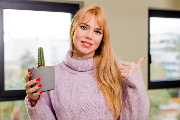 Young pretty woman holding a cactus at home interior