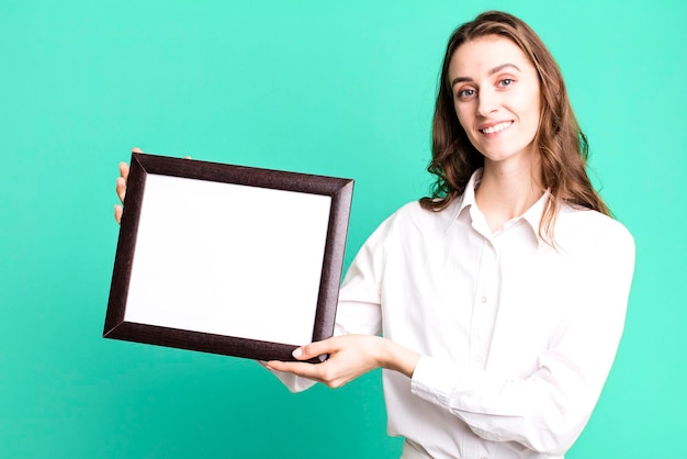 Young pretty woman holding an empty frame copy space