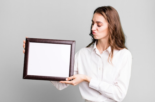 Young pretty woman holding an empty frame copy space