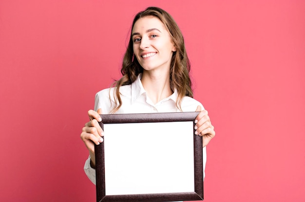 Young pretty woman holding an empty frame copy space