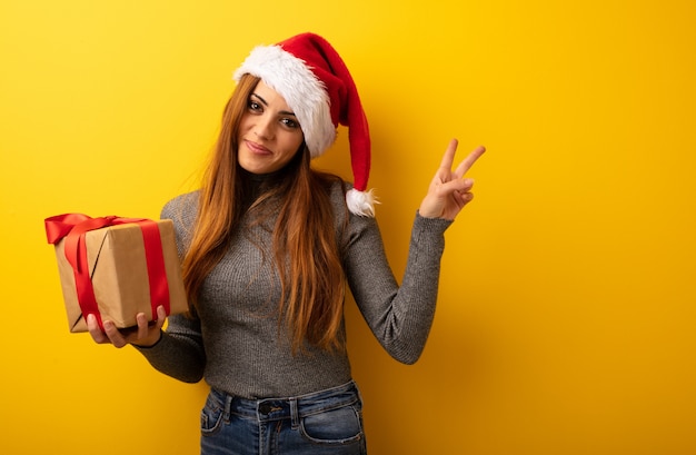 Young pretty woman holding gift doing a gesture of victory