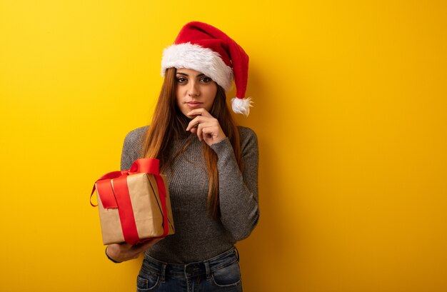 Giovane regalo grazioso della tenuta della donna che dubita e confuso