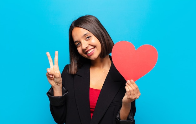 Giovane donna graziosa che tiene una carta del cuore