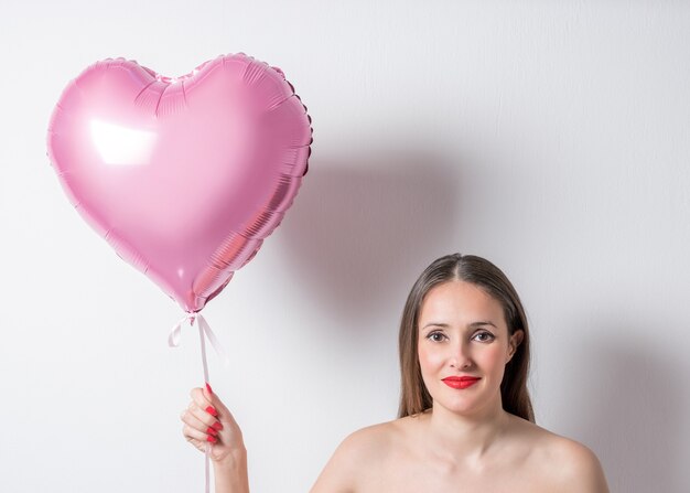 Молодая красивая женщина держит воздушный шар в форме сердца