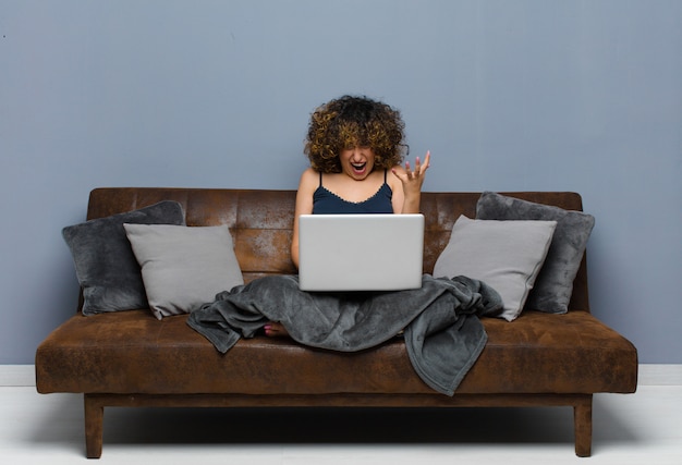 Photo young pretty woman at home, sitting on a sofa with a laptop