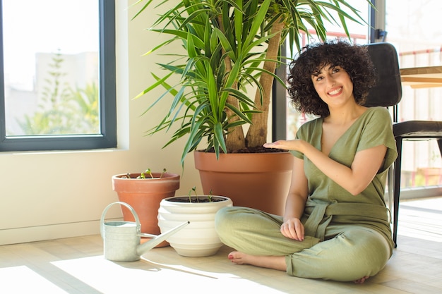 じょうろと植物を持つ自宅で若いきれいな女性