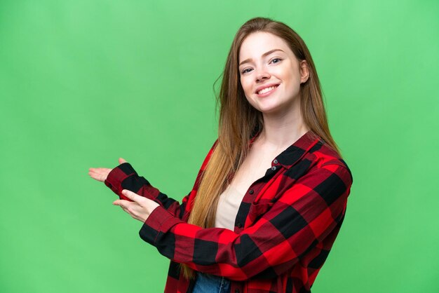 Young pretty woman over isolated chroma key background extending hands to the side for inviting to come