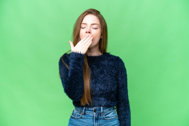 Young pretty woman over isolated chroma key background yawning and covering wide open mouth with hand