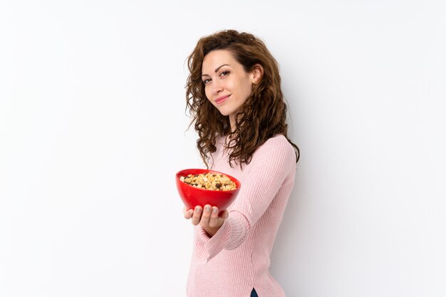 Young pretty woman over isolated wall holding a bowl of cereals