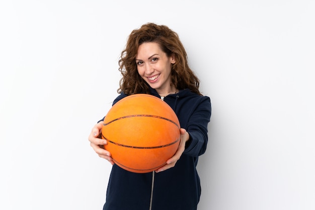 Young pretty woman over isolated wall with ball of basketball