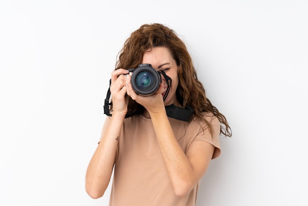 Young pretty woman over isolated wall with a professional camera