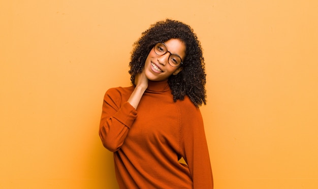 Young pretty woman laughing cheerfully and confidently with a casual, happy, friendly smile over orange wall