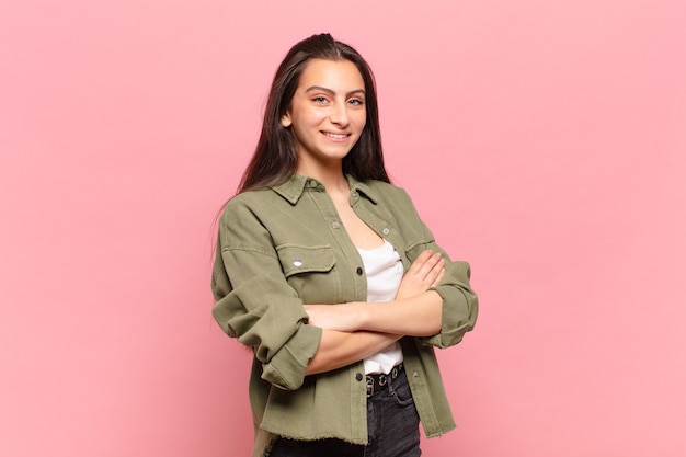 Photo young pretty woman laughing happily with arms crossed, with a relaxed, positive and satisfied pose