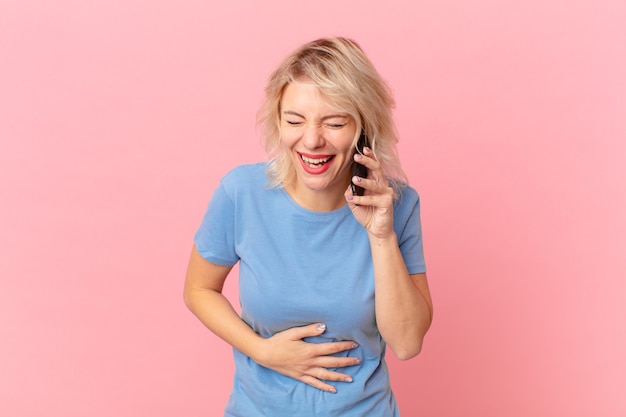 Young pretty woman laughing out loud at some hilarious joke. cell concept