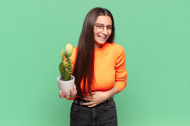 Young pretty woman laughing out loud at some hilarious joke, feeling happy and cheerful, having fun. cactus concept