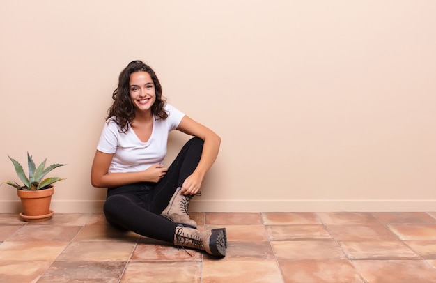 Young pretty woman laughing out loud at some hilarious joke, feeling happy and cheerful, having fun sitting a terrace floor