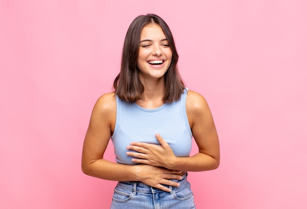 Young pretty woman laughing out loud at some hilarious joke, feeling happy and cheerful, having fun