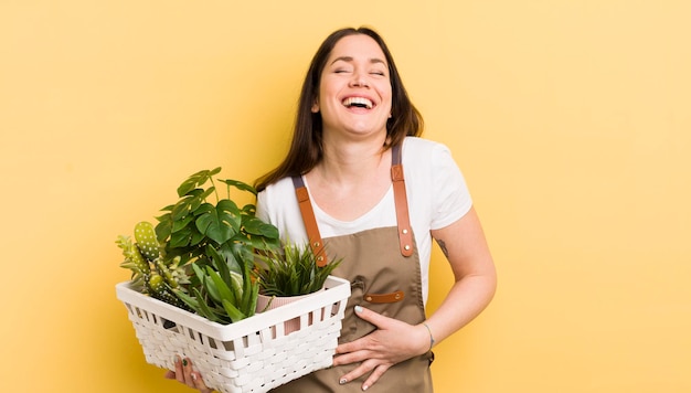 いくつかの陽気なジョーク植物の概念で大声で笑っている若いきれいな女性