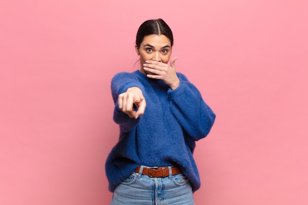 Young pretty woman laughing at you, pointing to camera and making fun of or mocking you