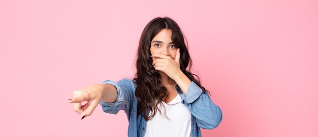 Young pretty woman laughing at you, pointing to camera and making fun of or mocking you