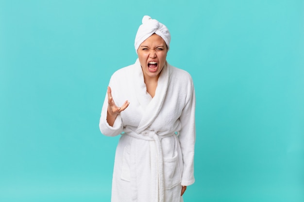 Young pretty woman looking angry, annoyed and frustrated and wearing bath robe after shower