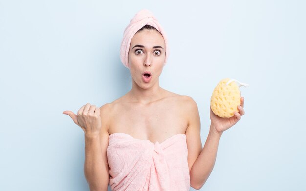 Young pretty woman looking astonished in disbelief. shower and sponge concept