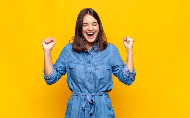 young pretty woman looking extremely happy and surprised, celebrating success, shouting and jumping
