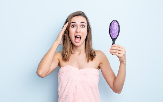 Young pretty woman looking happy, astonished and surprised. hairbrush concept