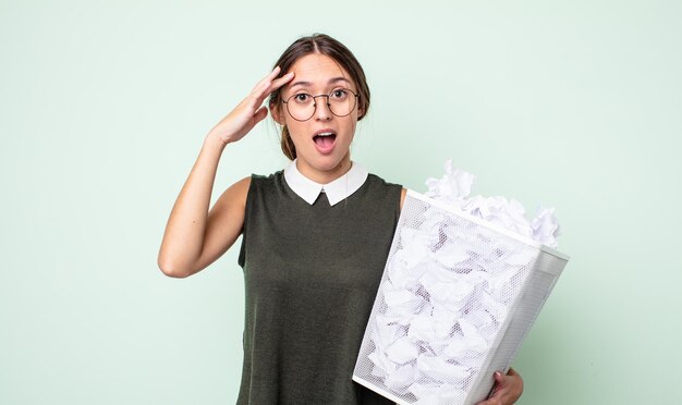 Young pretty woman looking happy, astonished and surprised. paper balls trash concept