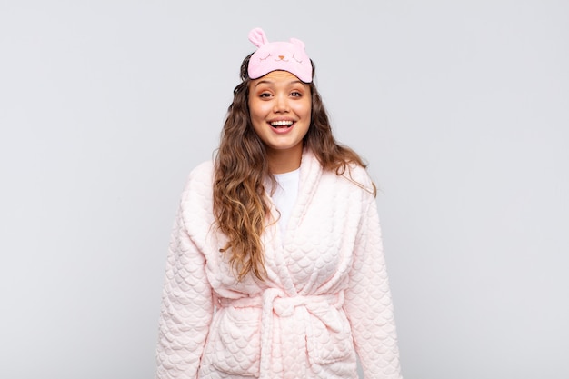 Young pretty woman looking happy and pleasantly surprised, excited with a fascinated and shocked expression wearing pajama